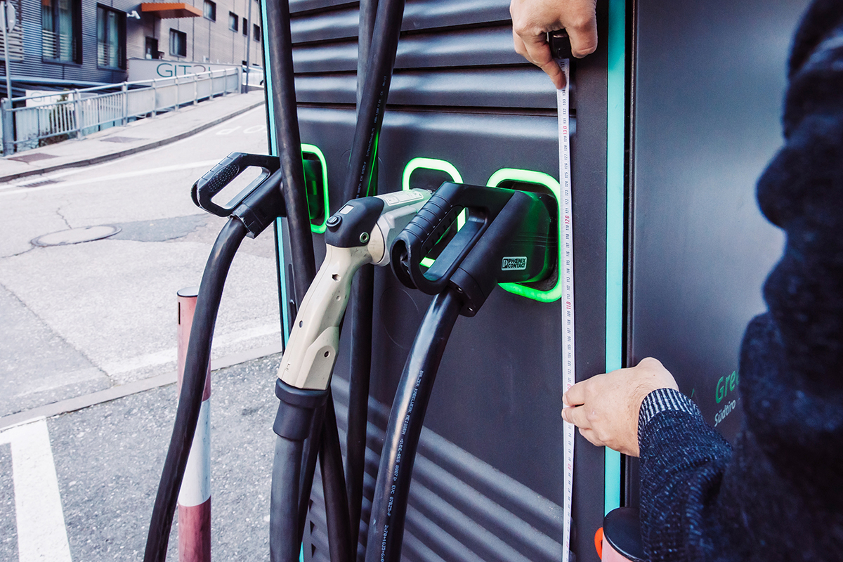 Close up of Independent L staff measuring height of EV charging station controls to evaluate accessibility in South Tyrol.